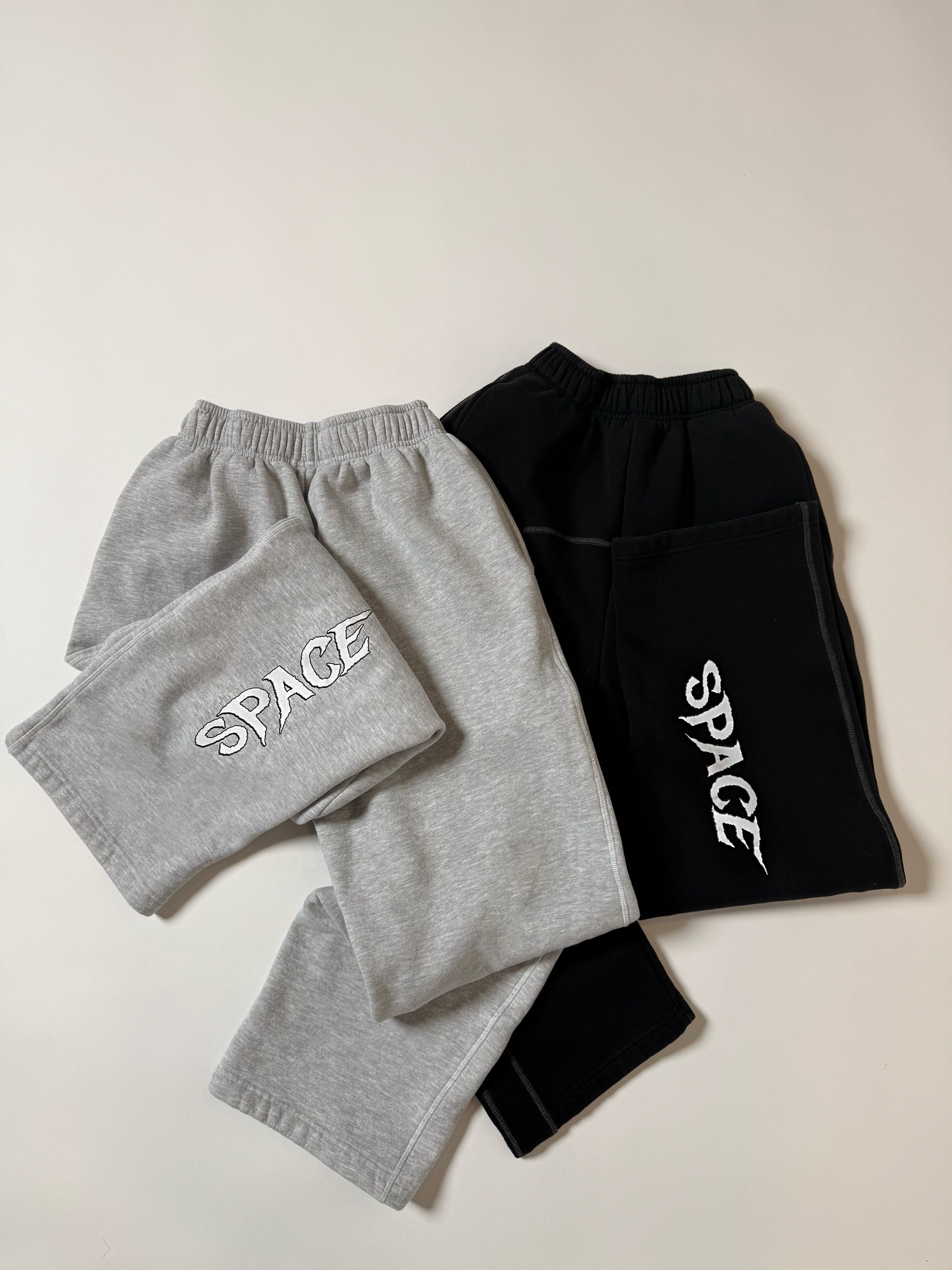 Gray and black sweatpants with 'SPACE' print on a light background