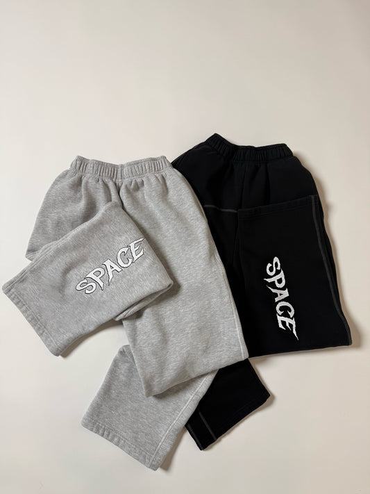 Gray and black sweatpants with 'SPACE' print on a light background